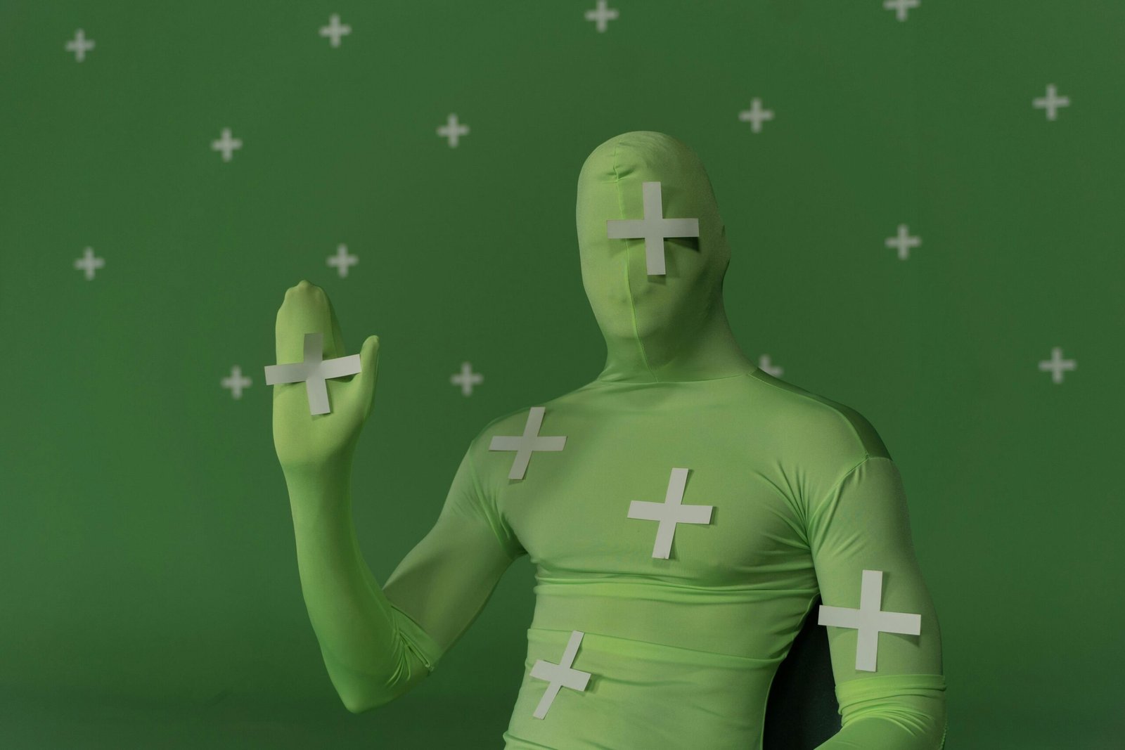 Person wearing a green screen suit with tracking markers for visual effects work.